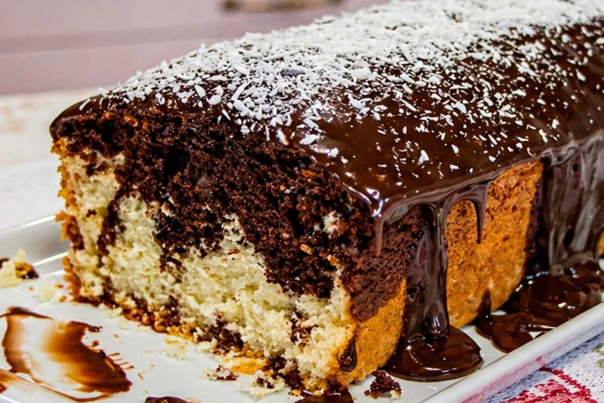 Bolo mesclado de coco com chocolate e cobertura cremosa, que