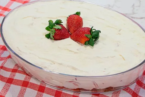 Torta gelada de leite ninho com morango na travessa, uma sob
