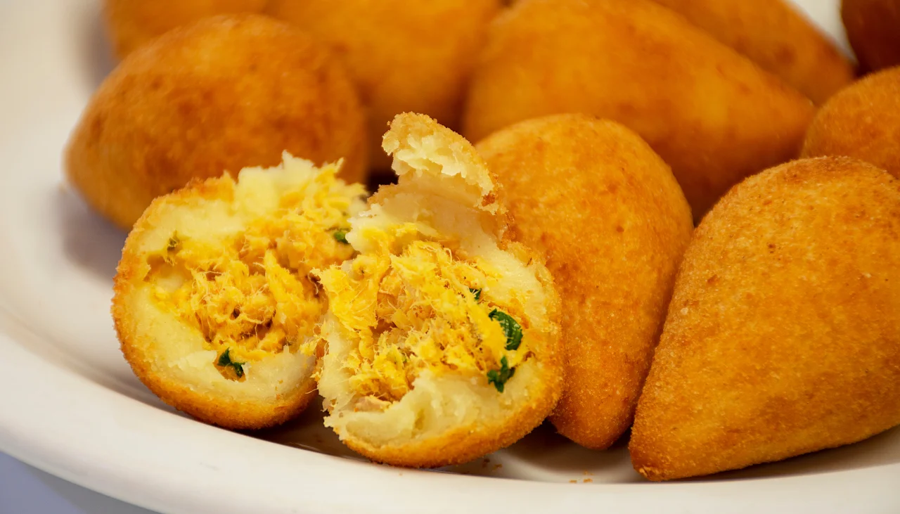 Coxinha de frango partida ao meio, mostrando seu delicioso recheio.