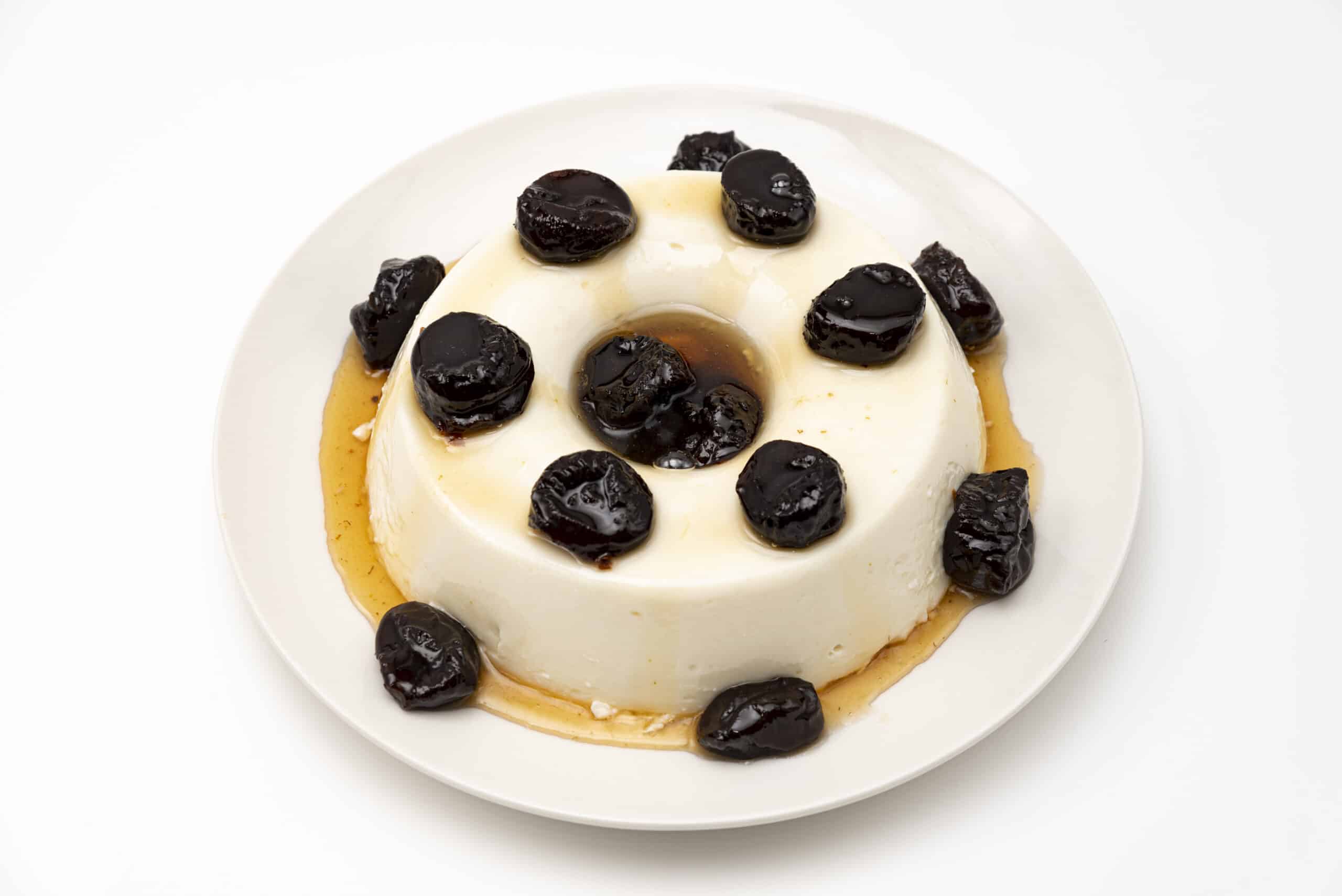 Delicious homemade traditional Brazilian dessert known as "Manjar" with plum syrup. Traditionally consumed at Christmas and New Year in Brazil. Isolated on white background. Top view.