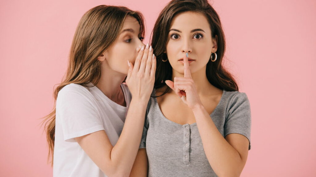 Mulher contando segredo para sua amiga